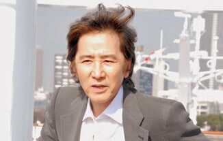 スーツ姿で立つ田村正和さん